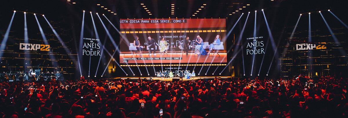 Imagem mostra palco iluminado com platéia cheia na CCXP 2022.