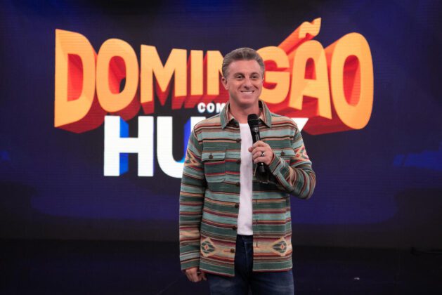Luciano Huck à frente do logotipo do Domingão, da TV Globo