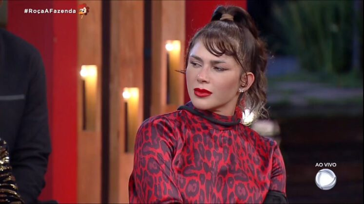 nadja pessoa está com roupa de onça vermeçlha e olhando para alateral