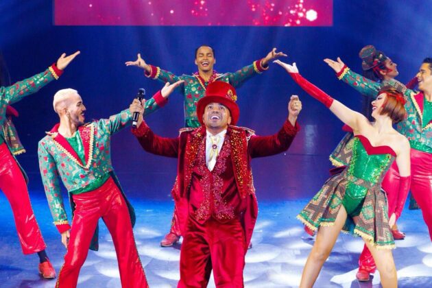 Tirullipa aparace com roupas vermelhas e seus bailarinos no picadeiro.