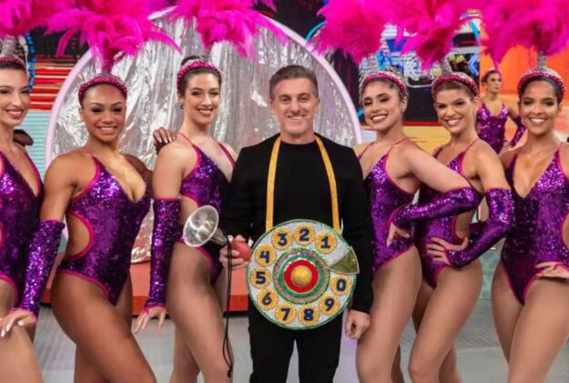 Luciano Huck vestido de Chacrinha rodeado por bailarinas
